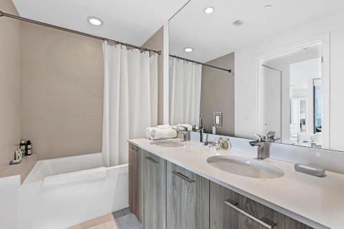 uma casa de banho com 2 lavatórios, uma banheira e um espelho. em Exclusive One-bedroom High-rise in Miami em Miami