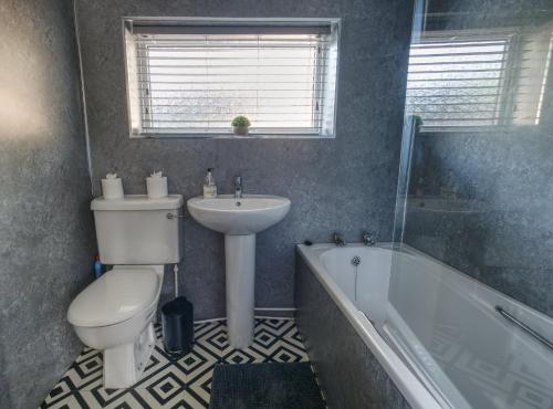 a bathroom with a toilet and a sink and a tub at #2 Limes by DerBnB, Modern 1 Bedroom Apartment, Free Parking, WI-FI & Netflix Near Royal Derby Hospital in Derby