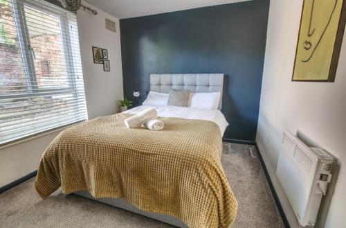 a bedroom with a large bed with a yellow blanket at #2 Limes by DerBnB, Modern 1 Bedroom Apartment, Free Parking, WI-FI & Netflix Near Royal Derby Hospital in Derby