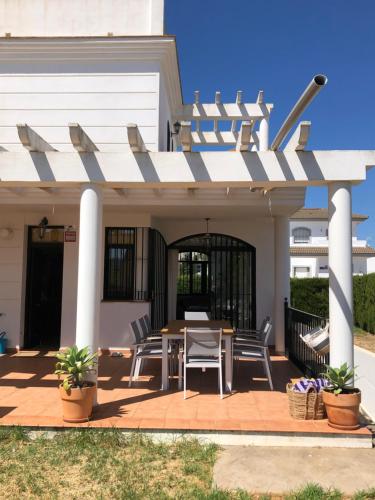 un patio con mesa y sillas bajo una pérgola en Holiday house with private pool, Costa de la Luz, en El Portil