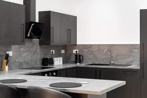 a kitchen with black cabinets and a marble counter top at Cowgate Luxury Apartments in Peterborough