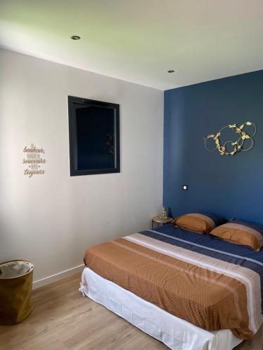 a bedroom with a bed with a blue wall at Appartement Cocooning entre lacs et montagnes in Saint-Alban
