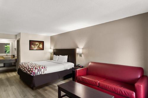 um quarto de hotel com uma cama e um sofá vermelho em Red Roof Inn Kingsland em Kingsland