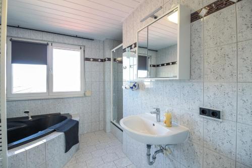 ein weißes Badezimmer mit einem Waschbecken und einem Spiegel in der Unterkunft nJoy! Modern & Zentral - WLAN - Badewanne - perfekt für Work & Travel in Göppingen