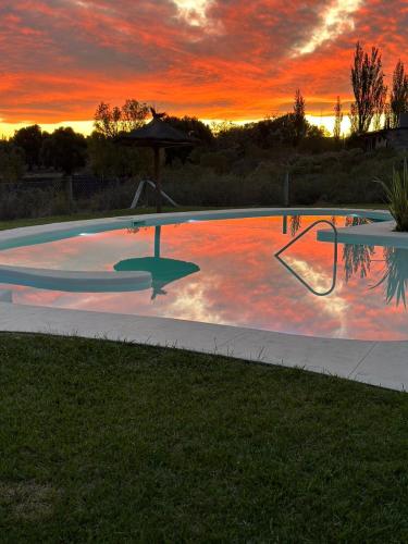a swimming pool with a sunset in the background at Cabañas Viento Andino in San Rafael