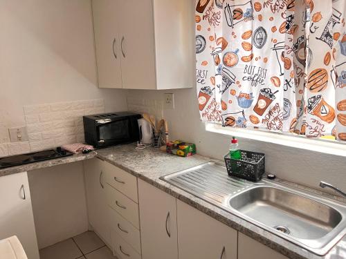 eine Küche mit einer Spüle und einer Mikrowelle in der Unterkunft S-star luxury Lounge in Roodepoort