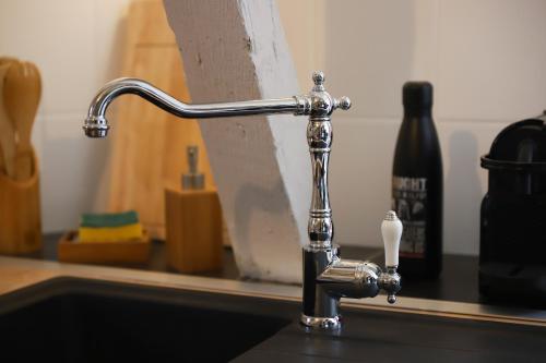 a chrome kitchen sink faucet with a toothbrush at La tanière du sorcier in Saumur