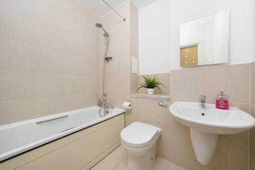 a bathroom with a sink and a toilet and a bath tub at Attractive London Apartment in London