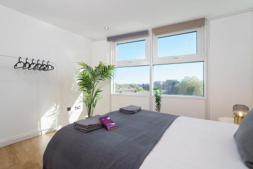 een witte slaapkamer met een groot bed en 2 handdoeken bij Attractive London Apartment in Londen