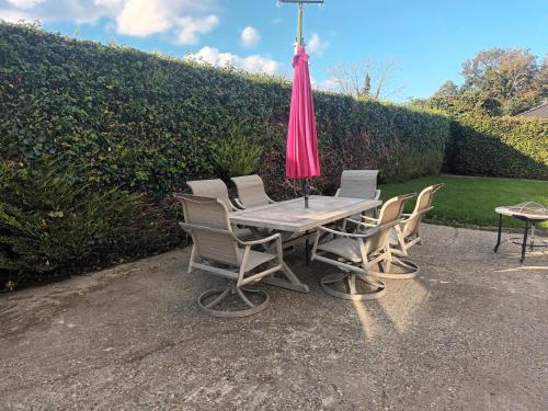 una mesa con sillas y una sombrilla rosa en Drumgauty Cottage en Strabane