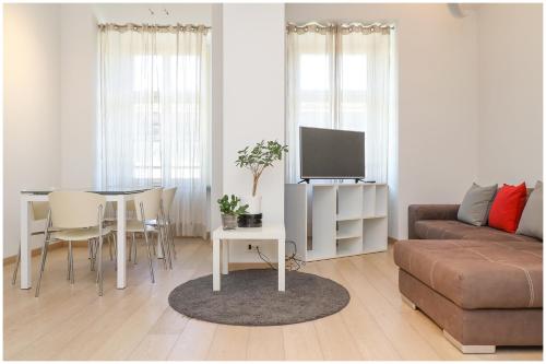 Il comprend un salon doté d'un canapé et d'une table avec une télévision. dans l'établissement Casa San Carlo nel cuore di Torino, à Turin