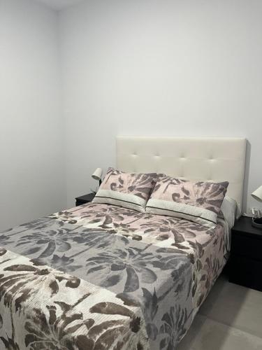 a bed in a bedroom with a white wall at Apartamentos La Meridian in Barcelona