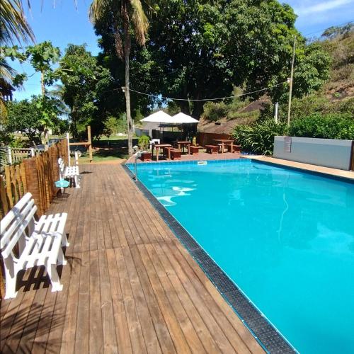 a swimming pool with chairs and a wooden deck at Pousada Moinho D'água in Guarapari