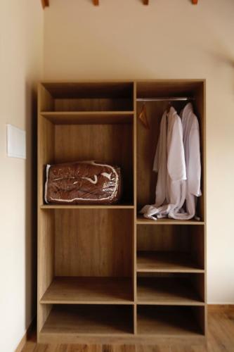 a closet with wooden shelves and white clothes at Chalé Pedra Madeira in São Bento do Sapucaí