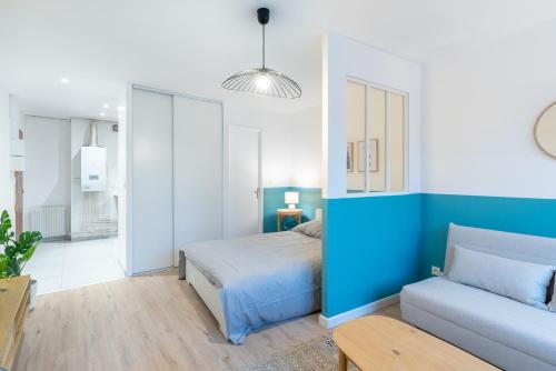 Dormitorio azul y blanco con cama y sofá en Studio centre Dax, en Dax