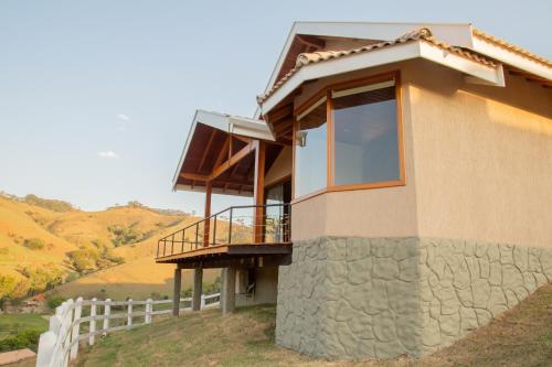 a house with a balcony on a hill at Chalé Pedra Madeira in São Bento do Sapucaí