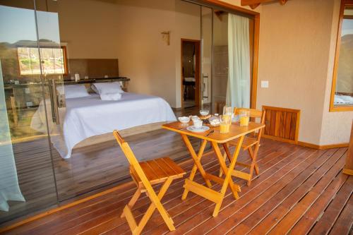 um quarto com uma cama, uma mesa e cadeiras em Chalé Pedra Madeira em São Bento do Sapucaí