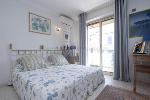 une chambre avec un lit et une grande fenêtre dans l'établissement Isadora, à Cannes