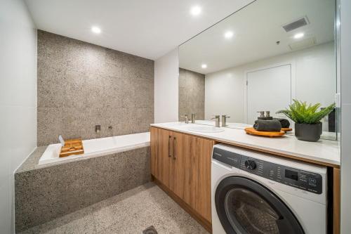 y baño con lavadora y lavamanos. en Ignite @ Park Tce Apartments, en Adelaida