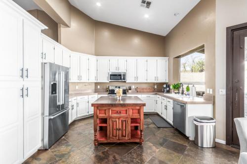 a large kitchen with white cabinets and a wooden island at Desert Sojourn in Phoenix