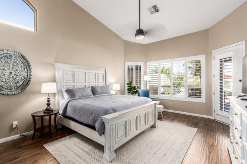 a bedroom with a white bed and two windows at Desert Sojourn in Phoenix