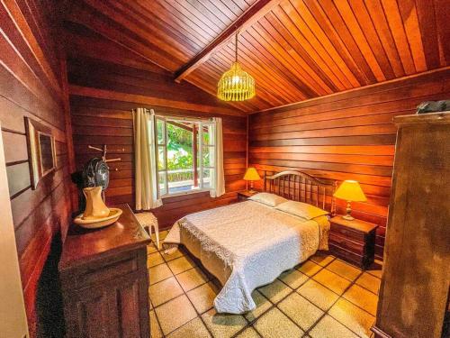 a bedroom with a bed in a wooden room at UBATUBA, SP - BRASIL - PRAIA DO FELIX - Casa do Aconchego in Ubatuba