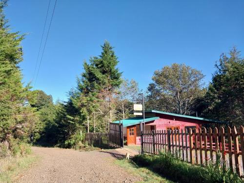 a red building with a fence next to a dirt road at Curuba Lodge in El Copey