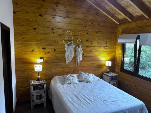 a bedroom with wooden walls and a bed with two tables at Casa y cabaña vista a las sierras in Villa Giardino
