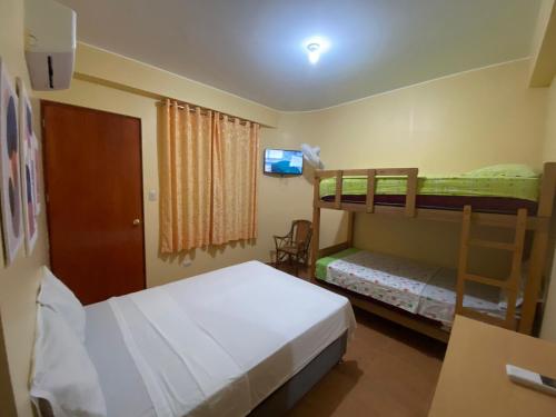 a bedroom with two bunk beds and a television at Hospedaje Ola Marina in Máncora