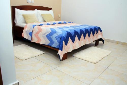 ein Schlafzimmer mit einem Bett mit Teppichen auf dem Boden in der Unterkunft Appartement meublé 2 pièces rez de chaussée, Résidence Nehemie in Abidjan