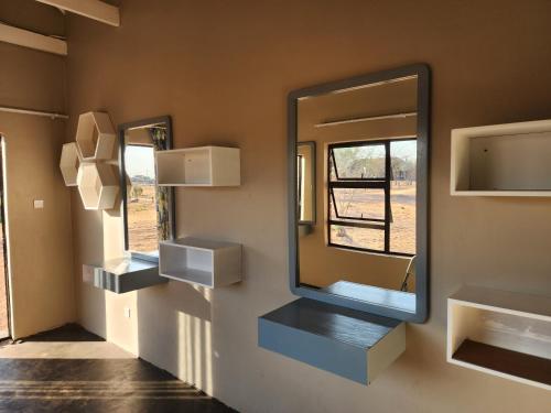 a mirror on the wall of a room with shelves at Makua Bush Hotel in Mochudi
