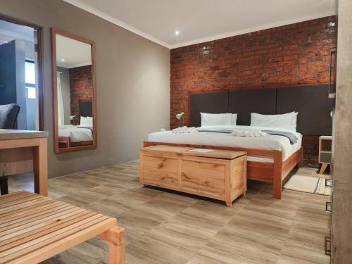 a bedroom with a bed and a brick wall at Makua Bush Hotel in Mochudi