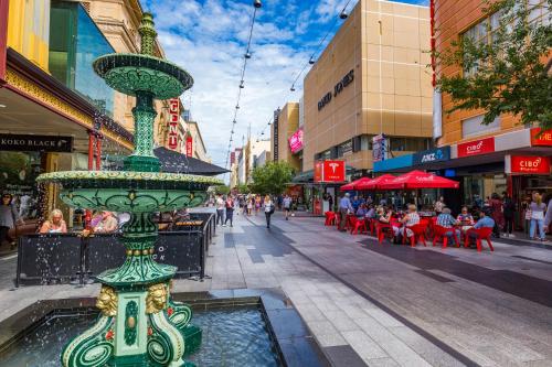 a street with a fountain in the middle of a city at Cozy Urban Chinatown Escape Adelaide CBD - Free parking in Adelaide