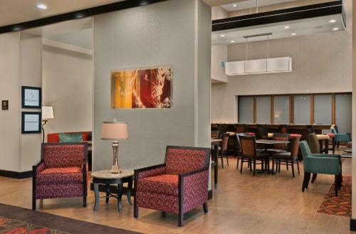 a lobby with chairs and tables and a dining room at Hampton Inn & Suites Tampa Northwest/Oldsmar in Oldsmar