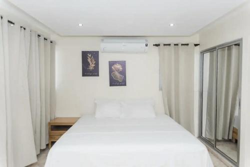 1 dormitorio con 1 cama blanca grande y cortinas blancas en Verde Bonavita, en Santiago de los Caballeros