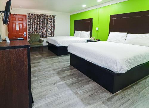 a hotel room with two beds and a green wall at Rodeway Inn San Antonio Lackland AFB - SeaWorld in San Antonio