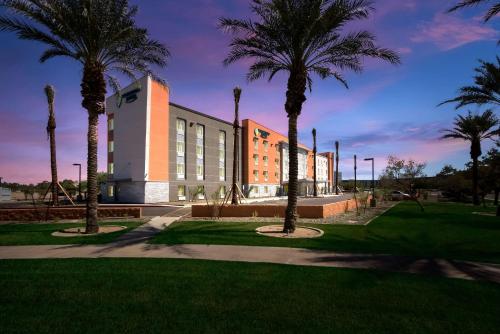 a building with palm trees in front of it at WoodSpring Suites Chandler Airport in Chandler