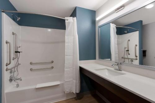 a bathroom with a tub and a sink and a mirror at WoodSpring Suites Chandler Airport in Chandler