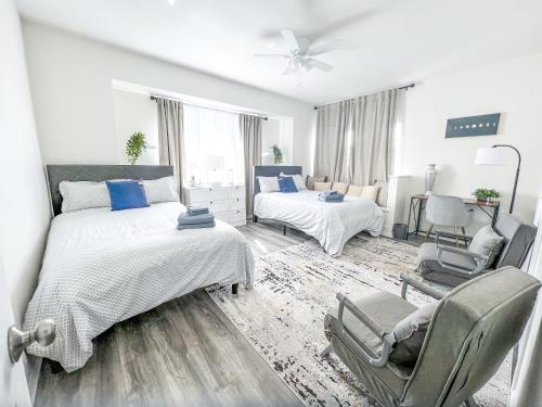 a white bedroom with two beds and a chair at 8 Beds Home with 4 Car Parking Space - Near DTLB in Long Beach