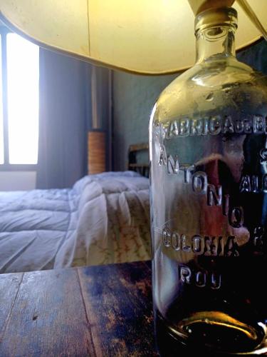 a bottle of alcohol sitting on a table in a bedroom at Posada San Gabriel in Colonia del Sacramento
