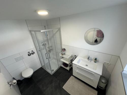 a white bathroom with a shower and a sink at Modernes Apartment mit eigener Terrasse & Garten in Aalen