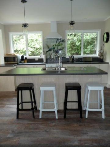 a kitchen with three bar stools and a sink at 28 Scarborough Tce in Hanmer Springs