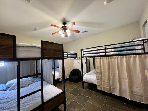 a room with four bunk beds and a ceiling fan at MyCrib Houston Hostel in Houston