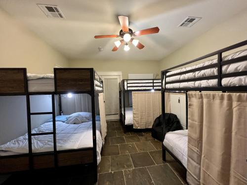 a room with four bunk beds and a ceiling fan at MyCrib Houston Hostel in Houston