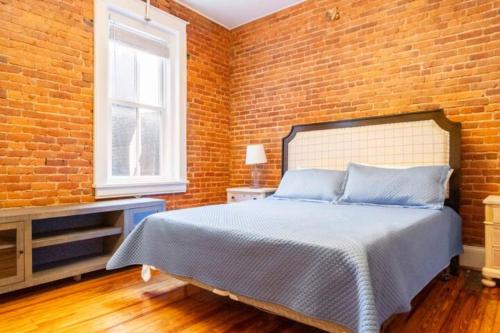 a bedroom with a brick wall and a bed at The Marilyn Monroe Loft. Central Downtown Location in Roanoke