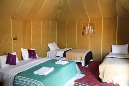 a room with two beds in a tent at Sahara Ousis Camp in Merzouga