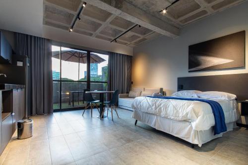 a bedroom with a bed and a table and a balcony at TOLIVE One Housi Recife by Carpediem in Recife