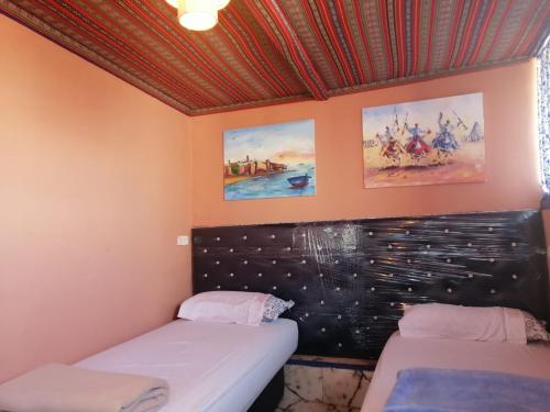 a room with two beds and paintings on the wall at Dar mahfoud in Rabat