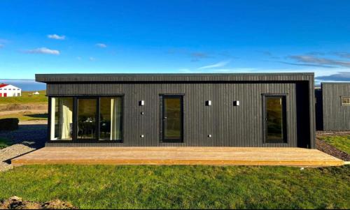 a small black house with a wooden deck at REY Stays - House in Höfn