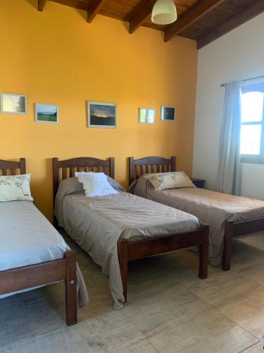 2 camas en una habitación con una pared amarilla en El Hornero en San Andrés de Giles